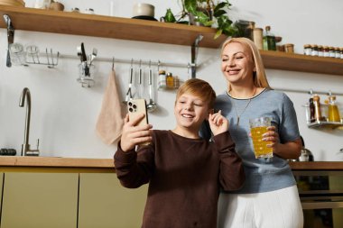 Annesiyle şık bir mutfakta gülümseyen bir çocuk, birlikte neşeli bir anı yakalıyor..