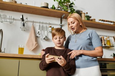 Bir anne ve küçük oğlu, birlikte yeni şeyler keşfeden akıllı bir telefonla neşeyle meşgul oluyorlar..