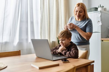 Bir anne, evinde dizüstü bilgisayar kullanırken kıkırdarken oğluyla iyi vakit geçirmekten zevk alır..