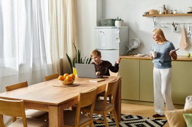Bir kadın oğluyla parlak bir mutfakta iş ve aile zamanını neşeyle dengeliyor..