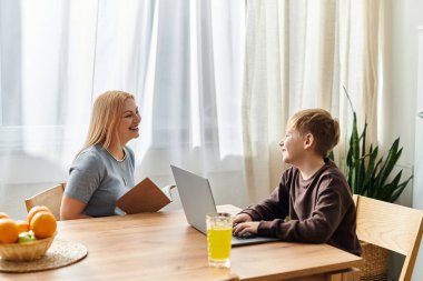 Neşeli bir anne ve oğlu neşeli bir anı paylaşıyor. Parlak, rahat bir masada aktiviteler yapıyorlar..