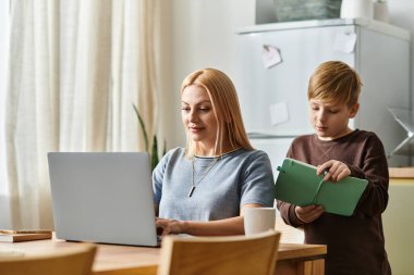 Annesinin yanında duran bir çocuk, dizüstü bilgisayarıyla sıcak, sevgi dolu bir yerde çalışır..