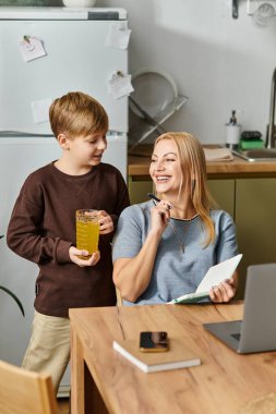 Bir anne ve oğul birlikte gülüyor, mutfak masalarında eğleniyorlar..