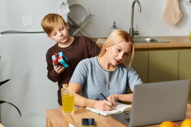 Bir anne yazısına odaklanır. Oğlu onu küçük bir hediyeyle şaşırtır..