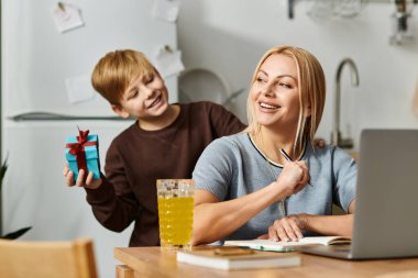 Bir anne mutlu bir şekilde gülümserken oğlu onu davet ettiği mutfakta bir hediyeyle şaşırtır..