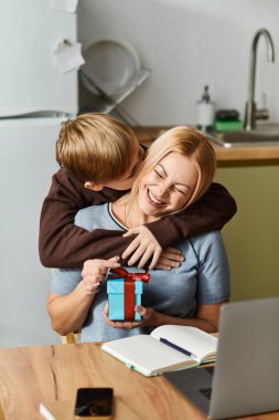 Bir anne, evinde özel bir hediyeyi paylaşırken oğlunun içten bir öpücüğünden zevk alır..