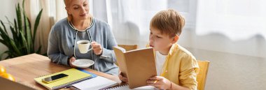 Bir anne, oğlu aydınlık bir sabahta mutfak masasında kitap okurken elinde bir fincan kahve tutar..