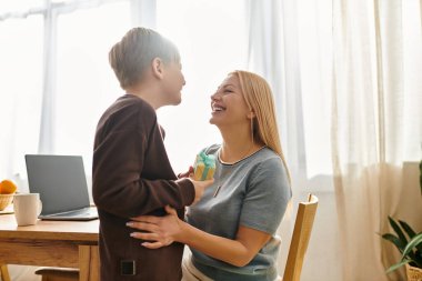 Bir anne ve oğul, evlerinin sıcaklığında birlikte gülerek neşeli bir bağ paylaşıyorlar..