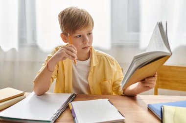 Samimi kıyafetli sevimli bir çocuk mutfaktaki masada malzemelerini çalışıyor..