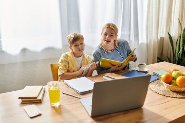 Bir anne ve oğul, mutfak masasında birlikte öğrendikleri mutlu anları paylaşırlar..