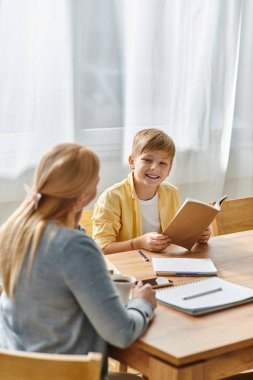 Bir kadın ve oğlu evde bir kitap okuyup bağlanırken birlikte güzel vakit geçiriyorlar..