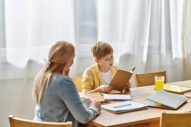 Bir anne, bir kitaba derinden odaklanmış olan oğluyla sakin bir anın tadını çıkarır..