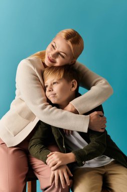 Sıcak bir odada, bir anne ve oğlu sıcak, gülümseyen bir kucaklaşmayı paylaşıyor..