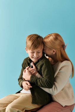 Neşeli bir anne oğlunu kucaklıyor, neşeli bir ortamda gülüşünü ve bağlılığını paylaşıyor..