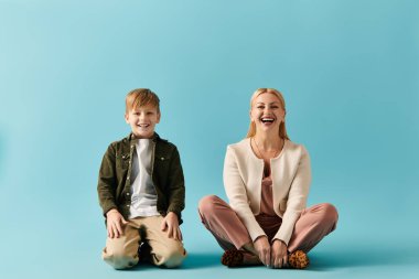 Bir anne ve oğul, sıcacık bir uzayda canlı mavi bir yüzey üzerinde birlikte otururken kahkahalarını paylaşıyor..