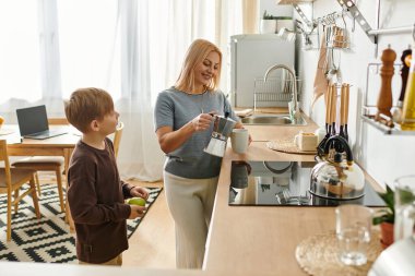 Bir anne ve oğlu, birlikte kahvaltı yaparken rahat bir mutfakta kaynaşırlar..