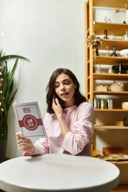 Modern bir kafede genç bir kadın telefonda menü seçeneklerini tartışırken meşgul görünüyor..