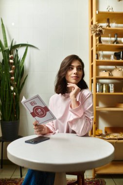 Kafe menüsünü okuyan genç ve güzel bir kadın sıcak bir masada, düşüncelere dalmış bir şekilde oturuyor..
