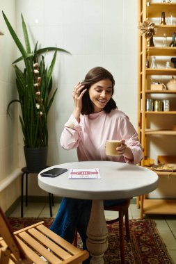 Gülümseyen kadın içkisini yudumluyor, bitkilerle dolu modern bir kafede huzurlu bir anın tadını çıkarıyor..