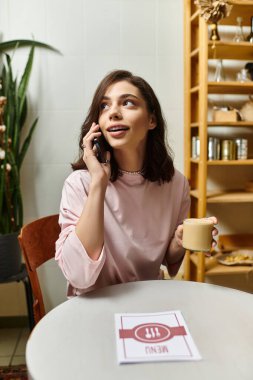 Modern bir kafede elinde fincanla konuşan genç ve güzel bir kadın..