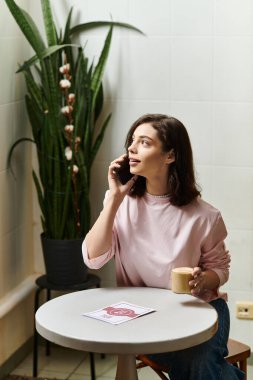 Modern bir kafede oturan genç bir kadın telefonla konuşurken elinde bir bardak tutuyordu..