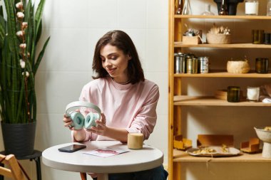 Canlı bir kafede dinlenen genç bir kadın, müzik seçeneklerini keşfederken içkisini yudumluyor..