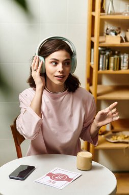 Güzel bir genç kadın kulaklık takıp gülümsüyor, bir kafede sohbet ediyor..