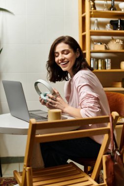 Gülümseyen genç bir kadın bilgisayarını kullanırken modern bir kafede serbest çalışıyor..