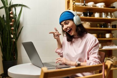 Genç bir kadın, kulaklık takarak şık bir kafede uzaktan kumandayla eğleniyor..