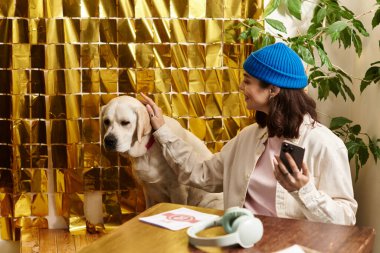 Genç bir kadın labradorunu nazikçe okşayıp sıcak bir ortam yaratırken rahat bir kafede dinleniyor..