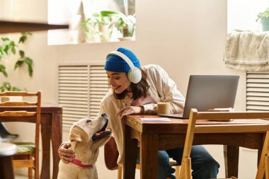 Genç bir kadın, labradoruyla hayat dolu bir kafede eğlenceli etkileşimlerden hoşlanır..
