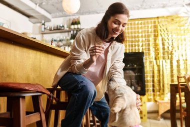 Genç bir kadın labradoruyla evcil hayvanlar için tasarlanmış modern bir kafede vakit geçiriyor..