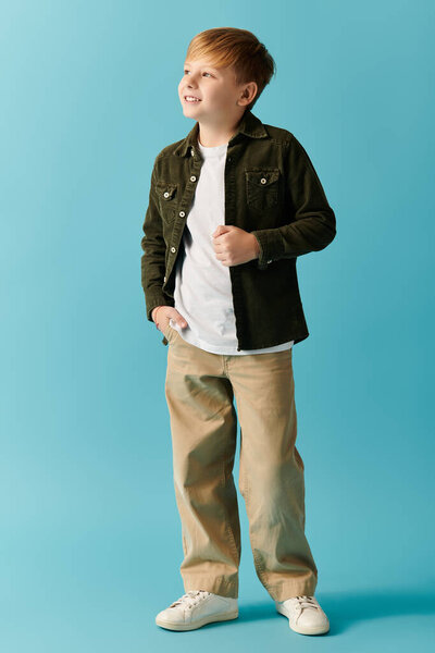 A smiling boy stands confidently against a bright blue backdrop, exuding warmth and joy.