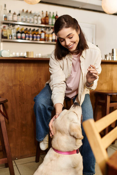 A young woman enjoys quality time with her labrador in a vibrant pet friendly cafe atmosphere.