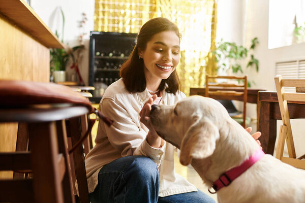 A young woman shares a joyful interaction with her labrador in a stylish pet friendly cafe.