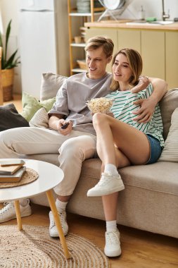 Sevgi dolu bir çift patlamış mısırı sever ve evdeki rahat bir kanepede birlikte güler..