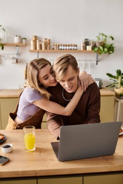 Sevgi dolu bir çift, modern mutfaklarında dizüstü bilgisayarla uğraşırken birbirlerine eşlik etmekten zevk alır..