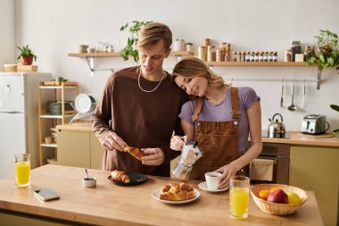 Sevgi dolu çift kahvaltıda gülüp kaynaşırken şık mutfaklarında sıcaklıkla.