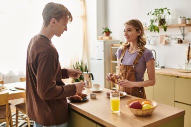 Modern mutfaklarında, bir çift sıcak bir sabah geçirir, kahvaltıyı gülümsemeyle paylaşır..