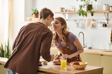 Sevgi dolu bir çift, bitkiler ve sıcaklıkla dolu şık bir mutfakta kahvaltıdan zevk alır..