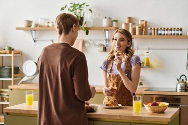 Genç bir çift sıcak, keyifli bir kahvaltıyı sıcak mutfaklarında paylaşır..
