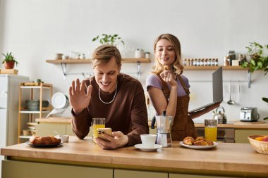 Genç bir çift şık mutfaklarında keyifli bir anı paylaşıyor, kahvaltılarının ve bağlantılarının tadını çıkarıyorlar..