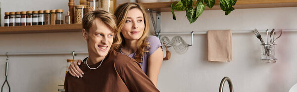 Young couple enjoys a playful and romantic hug while preparing a meal in their cozy kitchen.