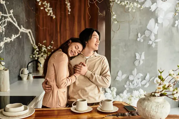 Bir çift kucaklaşır, zarif düğün dekorları ve çiçek aksanları arasında sıcacık gülümser..