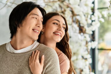 Bir çift, neşeli bir şekilde gülümseyerek canlı çiçeklerin arasında düğünlerine hazırlanıyor..