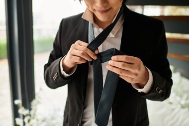 Genç ve yakışıklı bir damat kravatını titizlikle düzeltir ve düğüne hazırlanır..