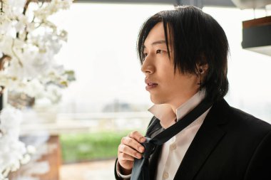 Yakışıklı bir damat kravatını evin içinde çiçeklerle süslüyor..