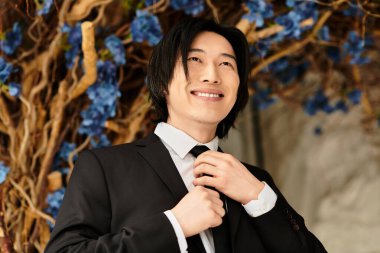 Genç bir adam büyüleyici çiçeklerle çevrili düğününe hazırlanırken cazibesini ve tarzını sergiler..