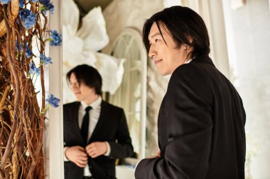 Sivri takım elbiseli genç bir adam yansımasını kontrol eder, düğün gününden önce neşe saçar..