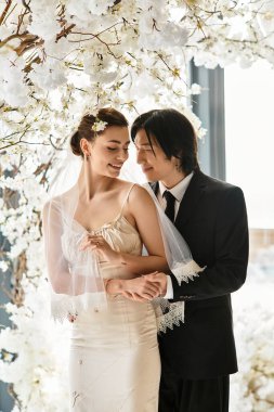 Genç bir çift, güzel çiçeklerle çevrelenmiş, sevgi saçan, mutlu bir şekilde kucaklaşır..